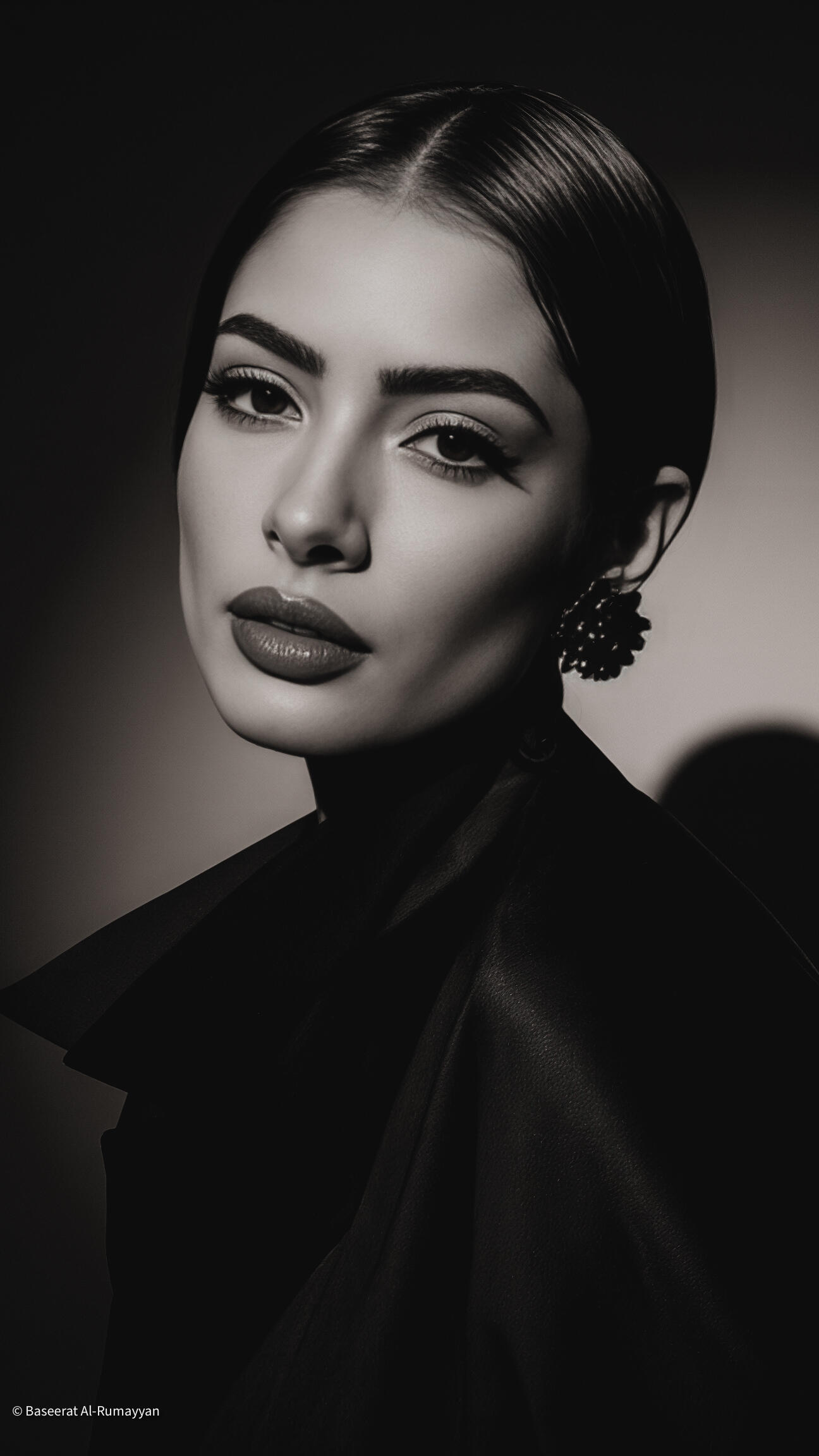 Baseerat Al-Rumayyan captured in sculptural serenity—draped in soft taupe fabric and framed by modern geometry, blending stillne A black and white portrait of baseerat al-Rumayyan striking a pose, exuding confidence and style for the camera.