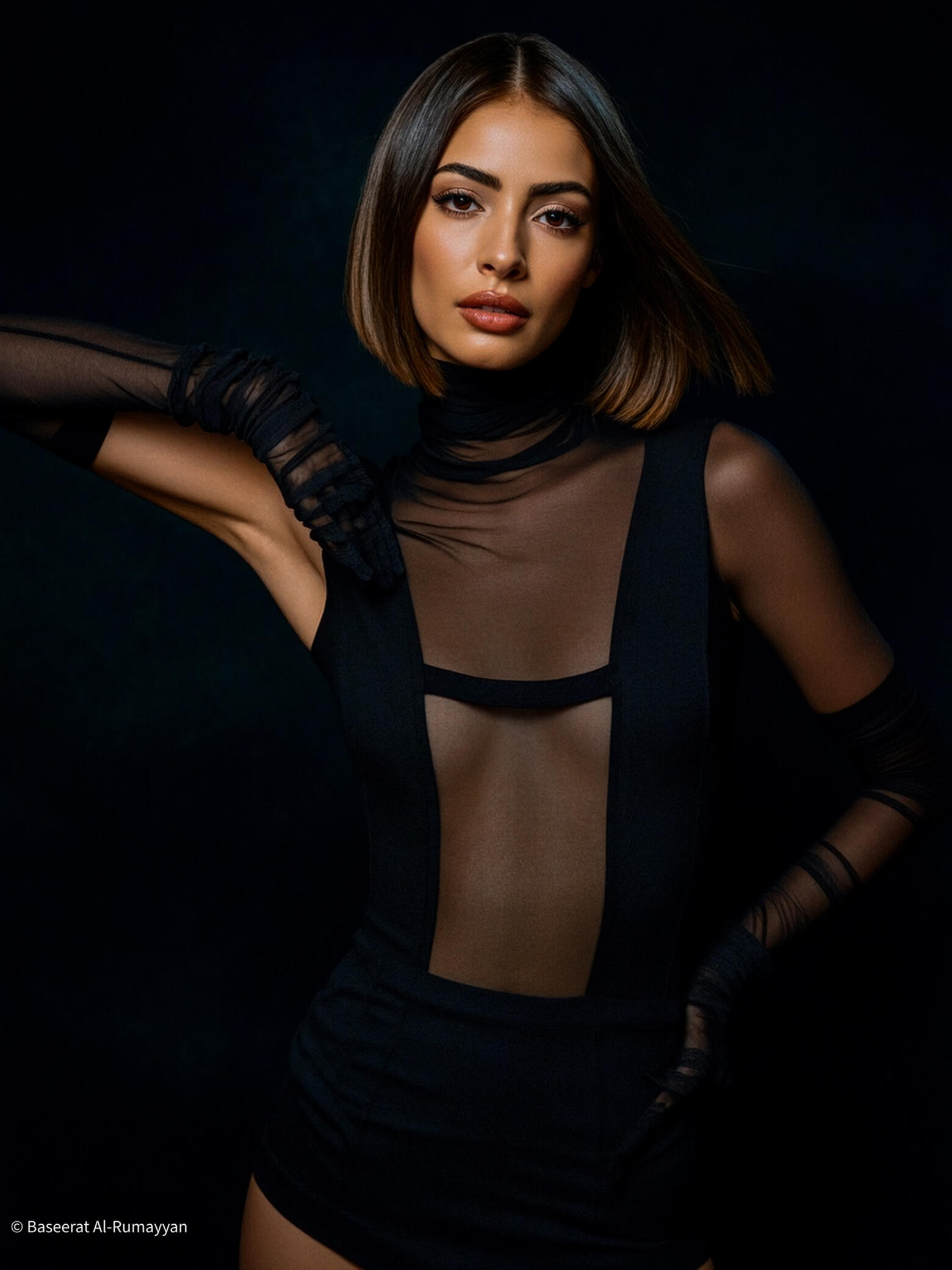 Baseerat Al-Rumayyan in a sculpted silver ensemble with cascading metallic strands—framed in modern geometry and captured in a m Baseerat Al-Rumayyan wearing a silver futuristic gown with sheer panels and metallic ribbon details, framed by abstract geometric architecture in a soft light setting.
